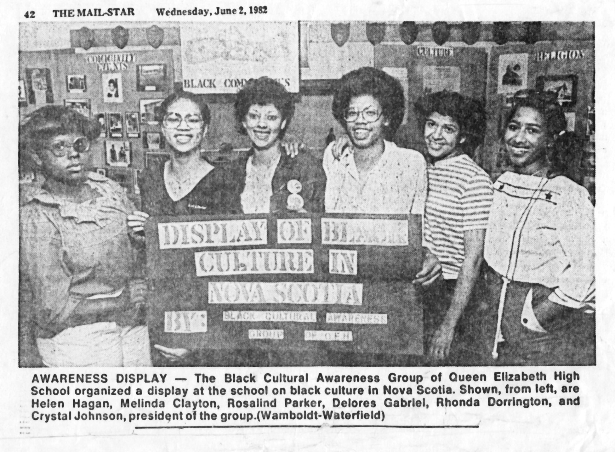 Six members of the Black Cultural Awareness Group at Queen Elizabeth High School stand behind a display titled “Display of Black Culture in Nova Scotia,” photographed for The Mail-Star newspaper in 1982.